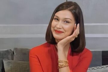 uśmiechnięta Bella Hadid w czerwonym ubraniu siedzi